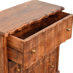 Close-up of a carved wooden chest of drawers with a warm medium-brown finish, brass knobs, and an open top drawer showing the interior, on a white background.